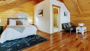 A log cabin bedroom with a bed, a sofa, and a small table. - Luxury White Mountain Adventure Cabin & Sauna (Bethlehem)