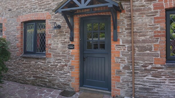A stone building with a dark blue door and a small window with a metal grill.