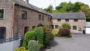 A stone building with multiple windows and a paved driveway.