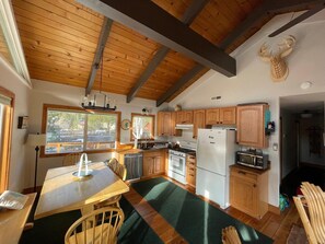 Una cocina con armarios de madera, una mesa de comedor y vistas al exterior.