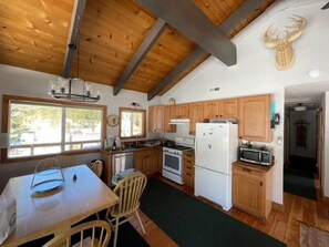 Una cocina con armarios de madera, una mesa de comedor, sillas, un refrigerador y un microondas.