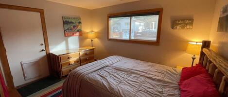 Ein Schlafzimmer mit Bett, Kommode, Fenster und Wanddekorationen.