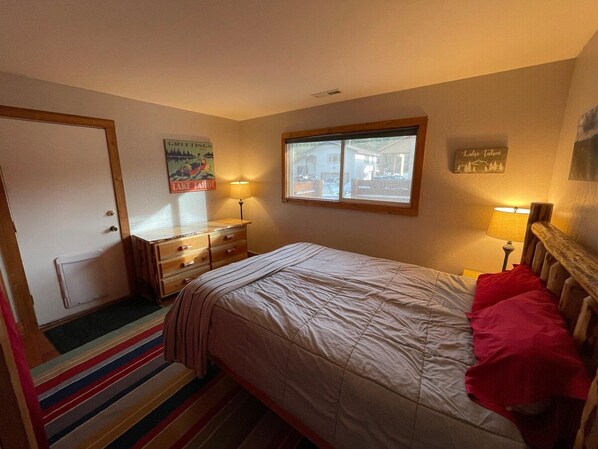 Un dormitorio con cama, cómoda, ventana y adornos en la pared.