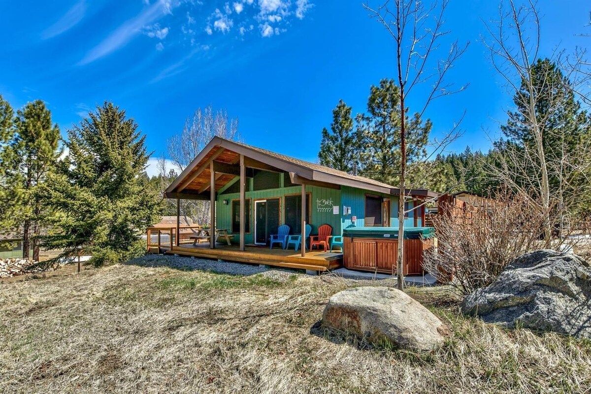 A cabin with a porch, a hot tub, and a deck area.