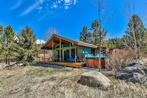 A cabin with a porch, a hot tub, and a deck area.
