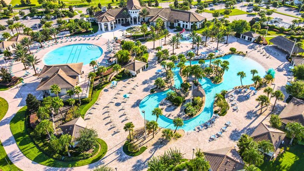 An aerial view of a resort with multiple swimming pools, sun loungers, and palm trees.