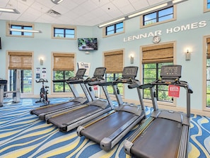 Un gimnasio con cintas de correr, bicicletas estáticas y una pantalla de televisión.