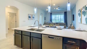 A modern kitchen with a central island, built-in dishwasher, and pendant lighting.