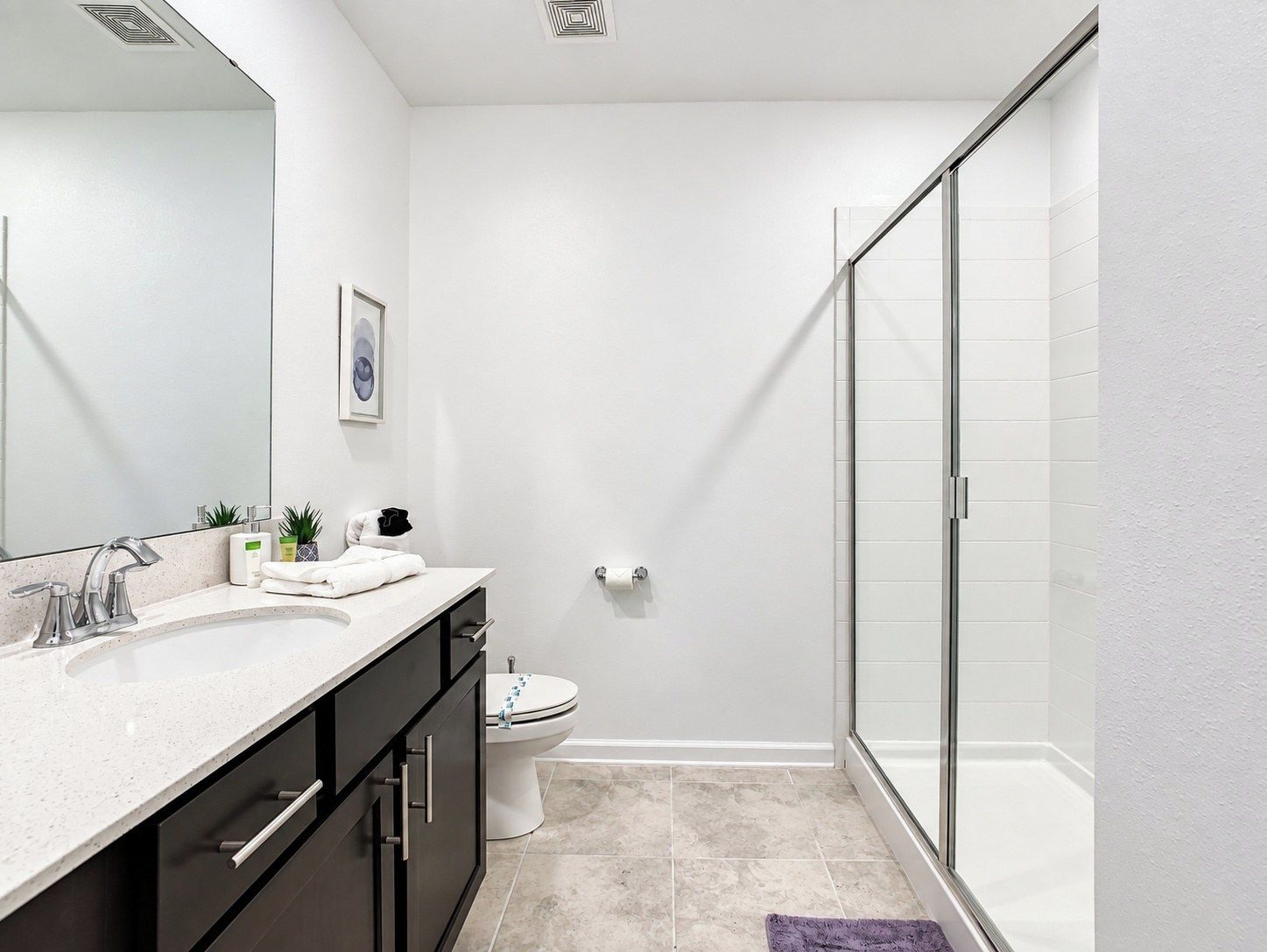 A modern bathroom with a shower, toilet, and vanity.