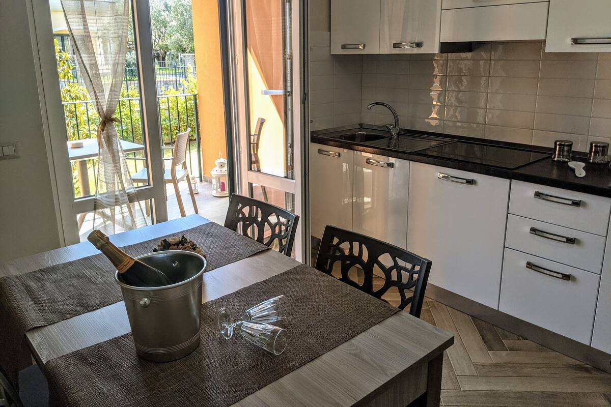 A modern kitchen with white cabinets, a black countertop, and a dining area with a table and chairs.