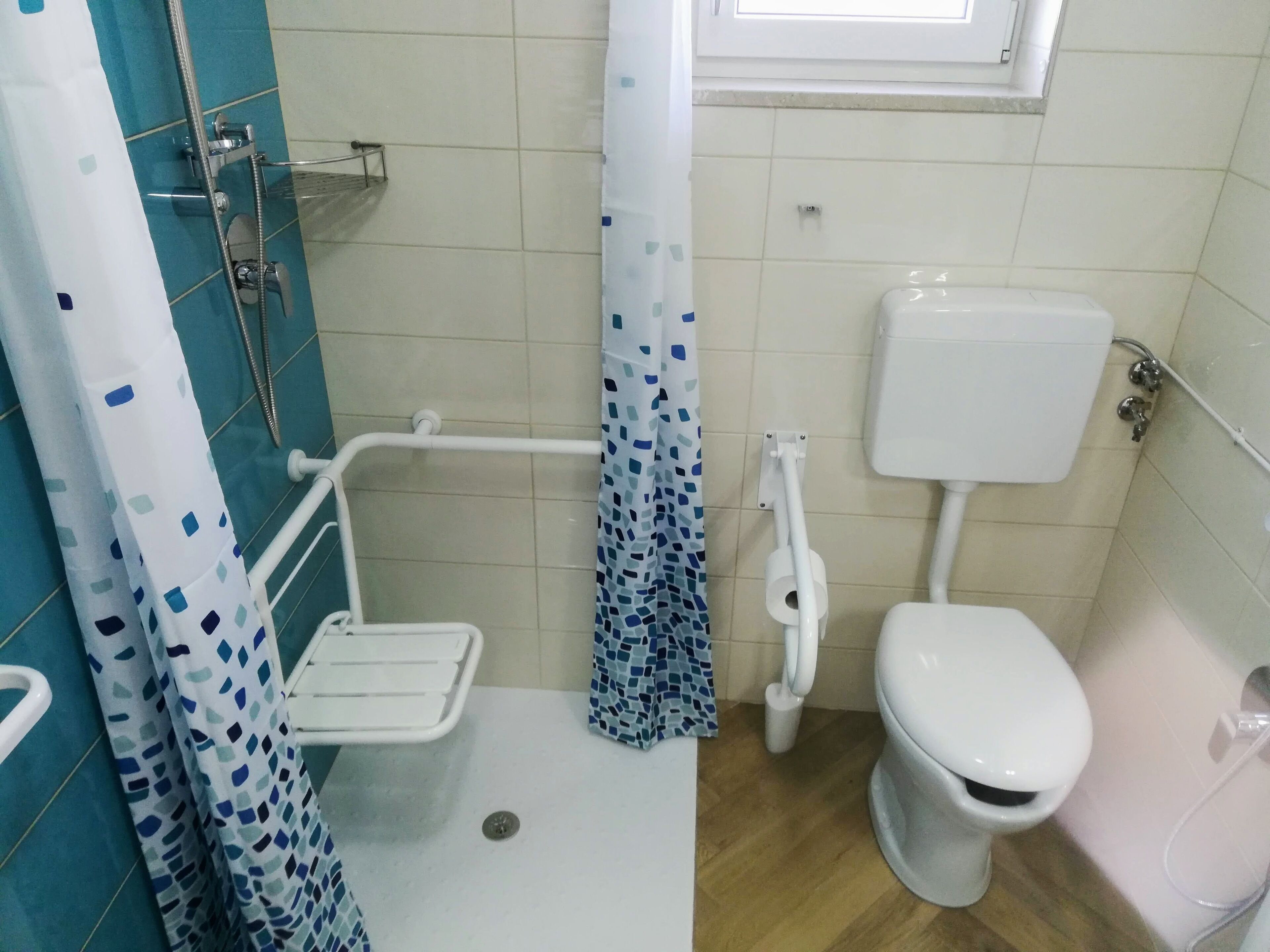 Une salle de bain équipée d’une douche, de toilettes et d’une barre d’appui.