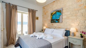 Una habitación de hotel con una cama grande, dos mesitas de noche con lámparas, una pared de piedra y un cuadro.
