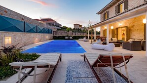 Un área de piscina con sillones de descanso y un espacio de estar techado.