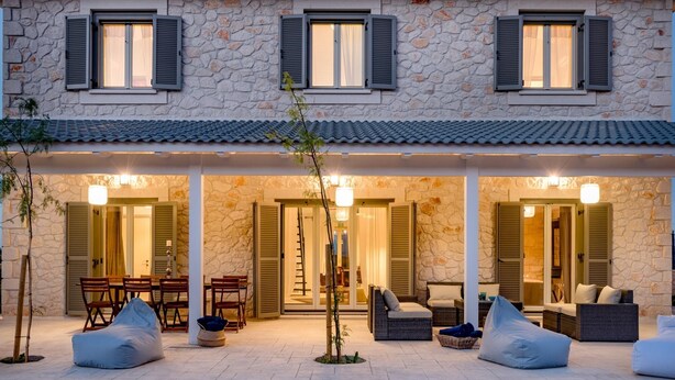 Un edificio de piedra con tres puertas abiertas que dan a un patio cubierto con mesas al aire libre.