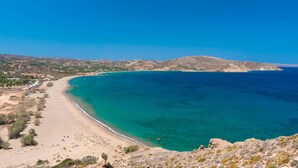 A coastal landscape with a clear blue sea, sandy beach, and distant hills. - Muses Beach Villas - Erato (Sitia)