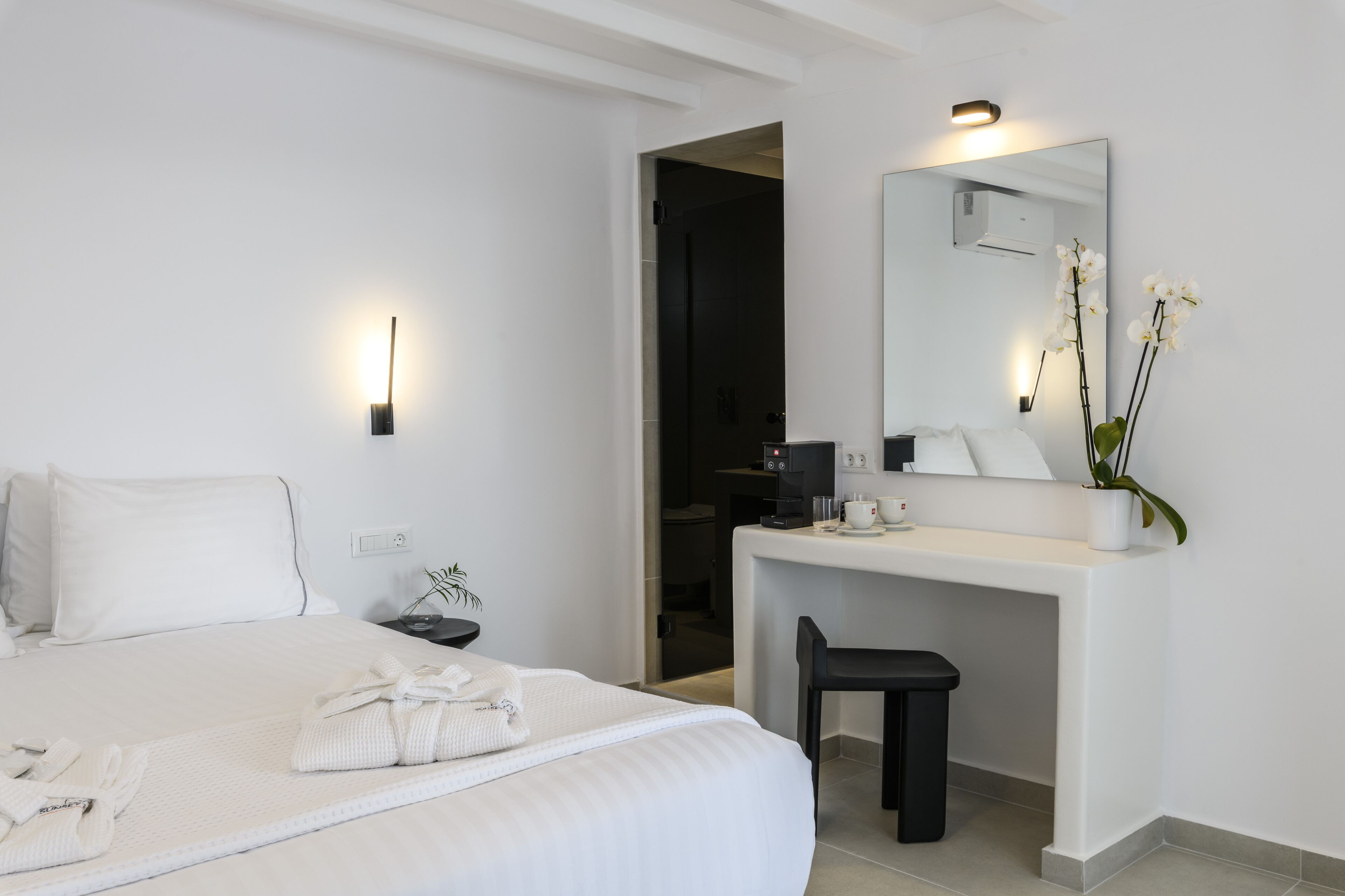 Ein Hotelzimmer mit Bett, Schreibtisch, Stuhl, Spiegel und einer Zimmerpflanze.
