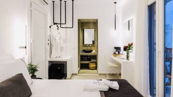 A modern hotel room with a bed, a desk, a bathroom, and a view of the outside.