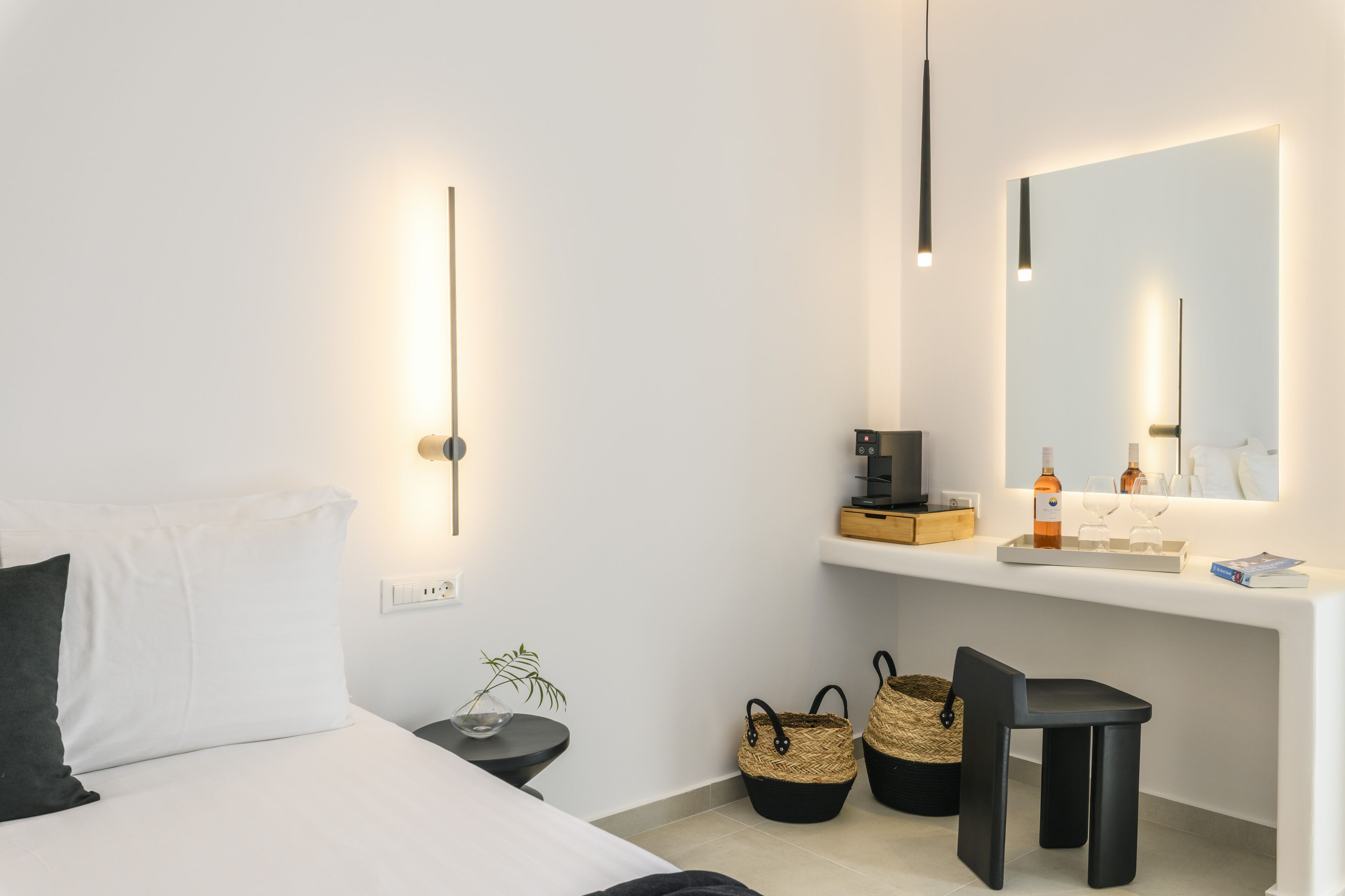 A modern hotel room with a bed, bedside table, lamp, and a large mirror.