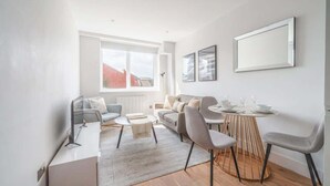 Een moderne woonkamer met een bank, salontafel en een eettafel met stoelen.