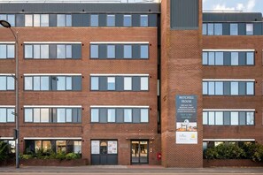 A multi-story brick building with a sign for Mitchell House advertising one and two-bedroom apartments.