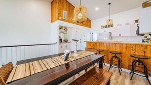 A modern kitchen with wooden accents, a central island, and bar stools. - OCTIPI Your SenSEAS - Kitty Hawk, Sea Dunes, Open All Year, Flex Stays, Pool, Clubhouse (Kitty Hawk)