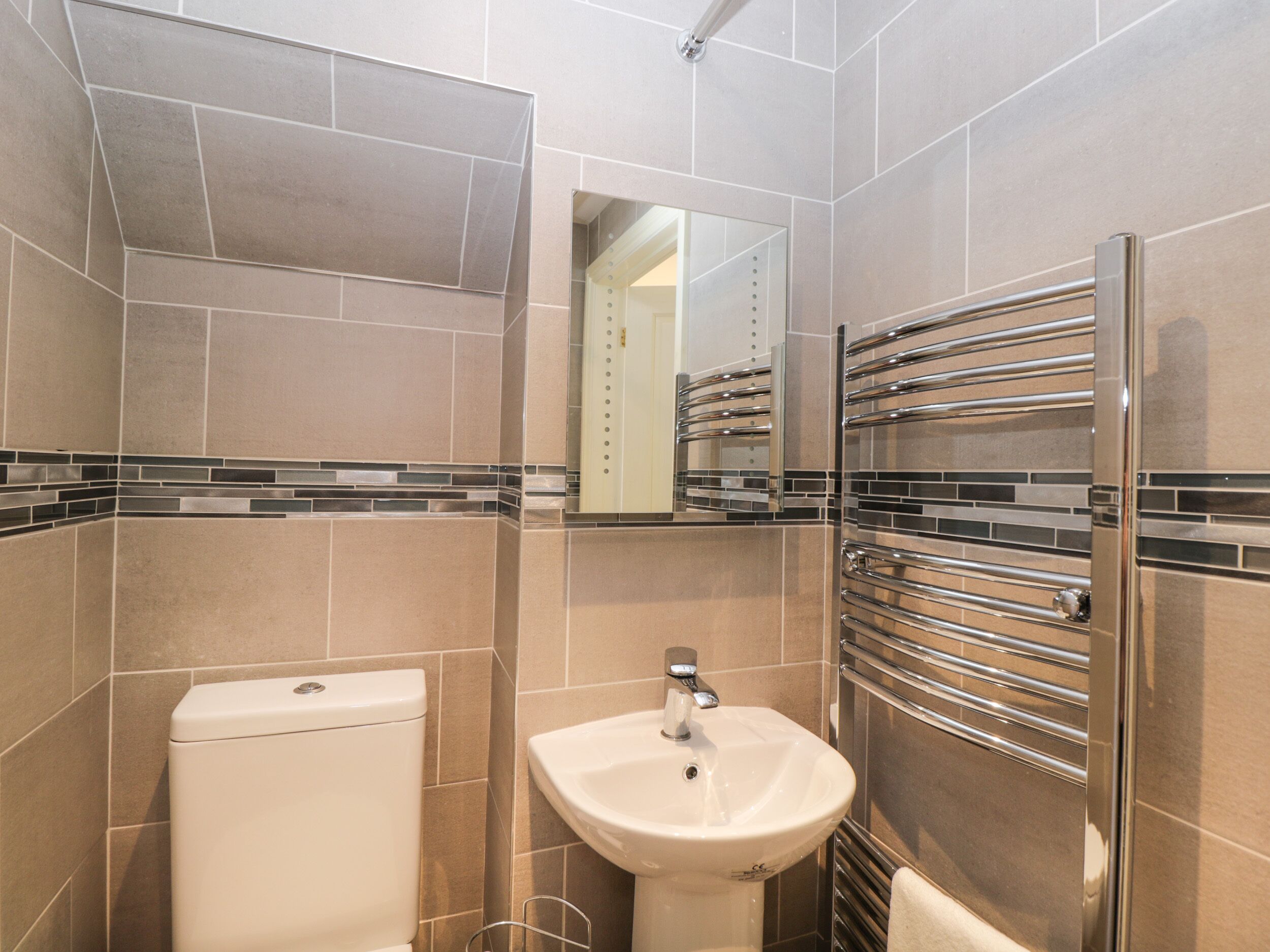 Un baño moderno con inodoro, lavabo y perchero para toallas.