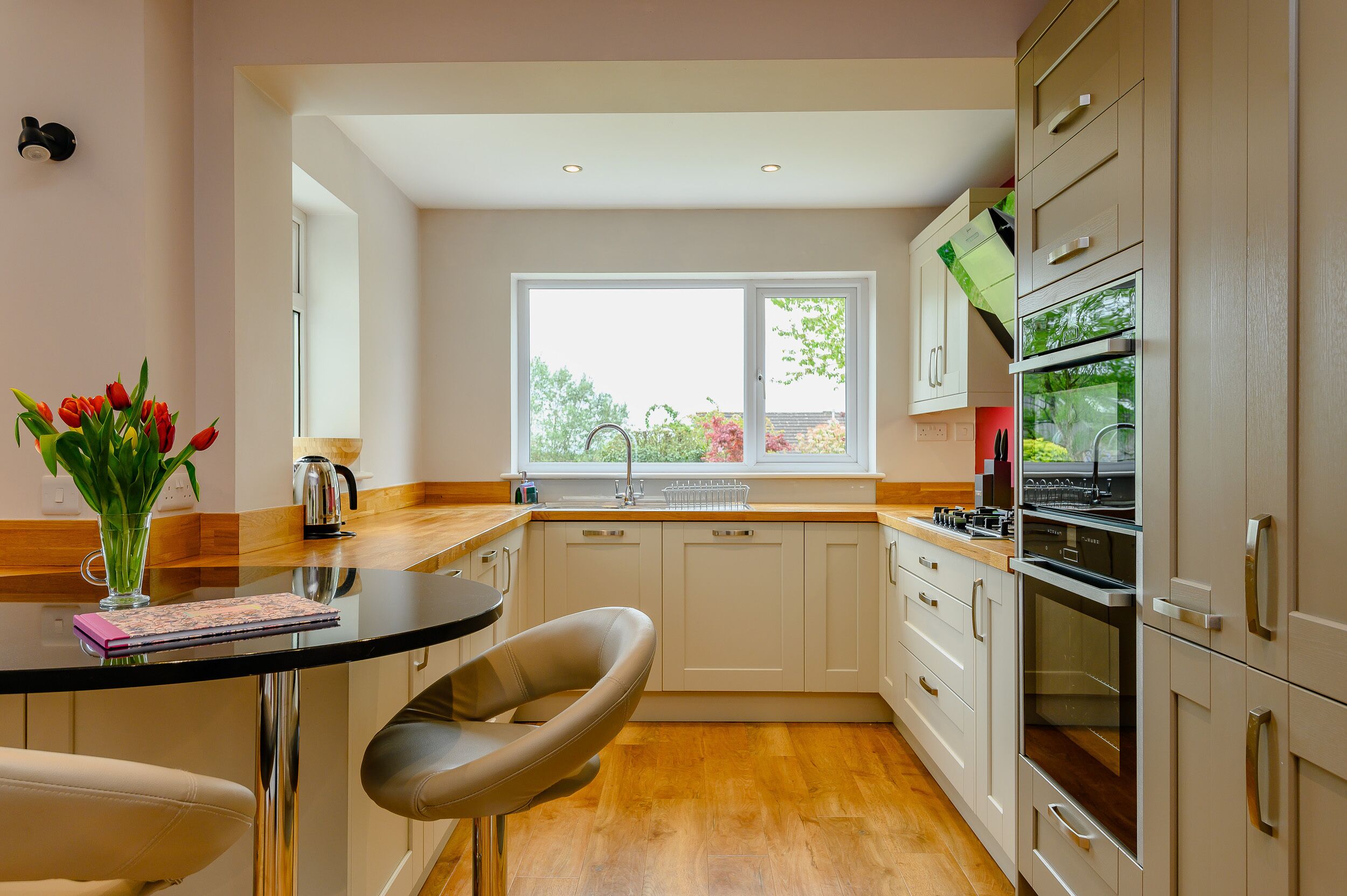 A modern kitchen with white cabinets, a black countertop, and a window with a view of trees.