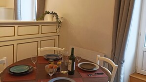 Een eettafel gedekt met borden, glazen en een fles wijn, omringd door witte stoelen.