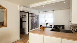 A modern kitchen with a wooden countertop, a sink, and a bowl of fruit. There is a window with curtains and a plant on the windowsill. - Champollion Appartment : A/C + Netflix + Garage (Albi)