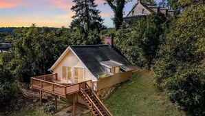 Ein kleines Haus mit einer Terrasse und einer Treppe, die zum Eingang führt.