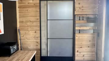 A modern kitchen with wooden walls, a black countertop, and a sliding door.