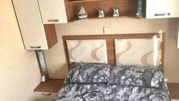 A bed with a marble-patterned bedspread, a wooden headboard, and a shelf above with decorative items.