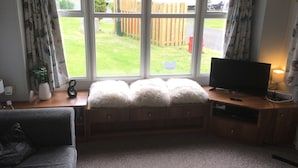 A cozy room with a wooden bench, a television, and a lamp.