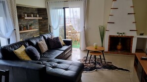 Un salon avec un canapé en cuir noir, une petite table en bois et une cheminée.