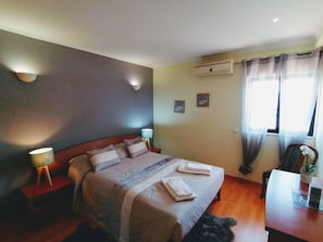 Une chambre d’hôtel avec un lit, des lampes de chevet, un bureau et une fenêtre avec des rideaux.