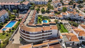 Un quartier résidentiel situé sur la côte, caractérisé par un bâtiment remarquable à la forme incurvée, surmonté d’une piscine sur le toit.