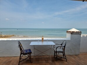 Una mesa con dos sillas y una botella de vino en una terraza con vistas al mar.