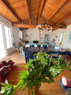 Una cocina amplia con vigas de madera, un comedor con sillas azules y un ventanal grande.