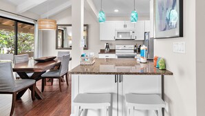 A modern kitchen with a dining area, white cabinetry, granite countertops, and pendant lighting. - ✨Walk2Beach-Renovated-Pools-Large Balcony- Pet Friendly-Sweet Magnolia✨ (Miramar Beach)