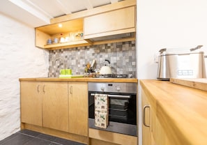 Kitchen area with a Bosch oven, sink, and kettle, featuring a geometric-patterned backsplash and cabinetry.