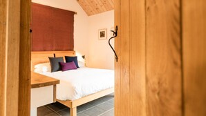 Un dormitorio con estructura de cama de madera, cabecera y cortina roja.