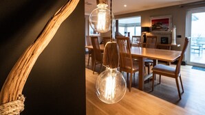 A dining area with wooden furniture and pendant lights. - An exceptional place to gather on the sea shore (Newport)