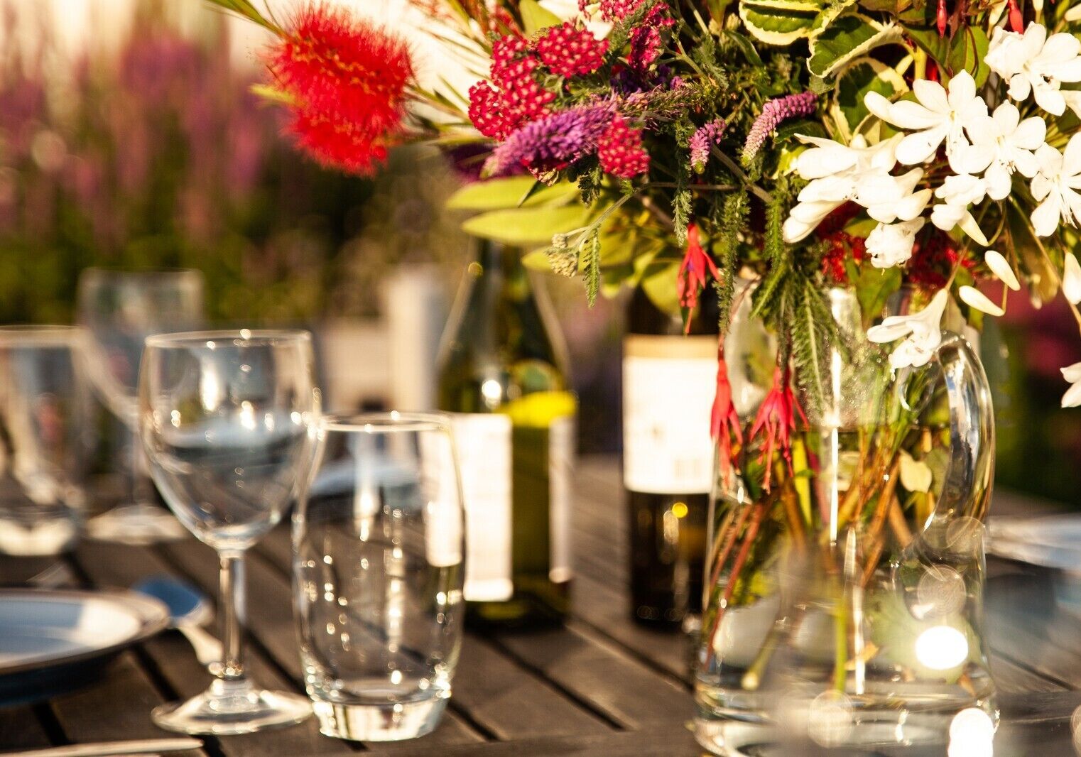 Una mesa dispuesta con copas de vino y un florero con flores.