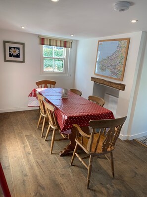 A dining room with a wooden table and chairs, a map on the wall, and a window with curtains.