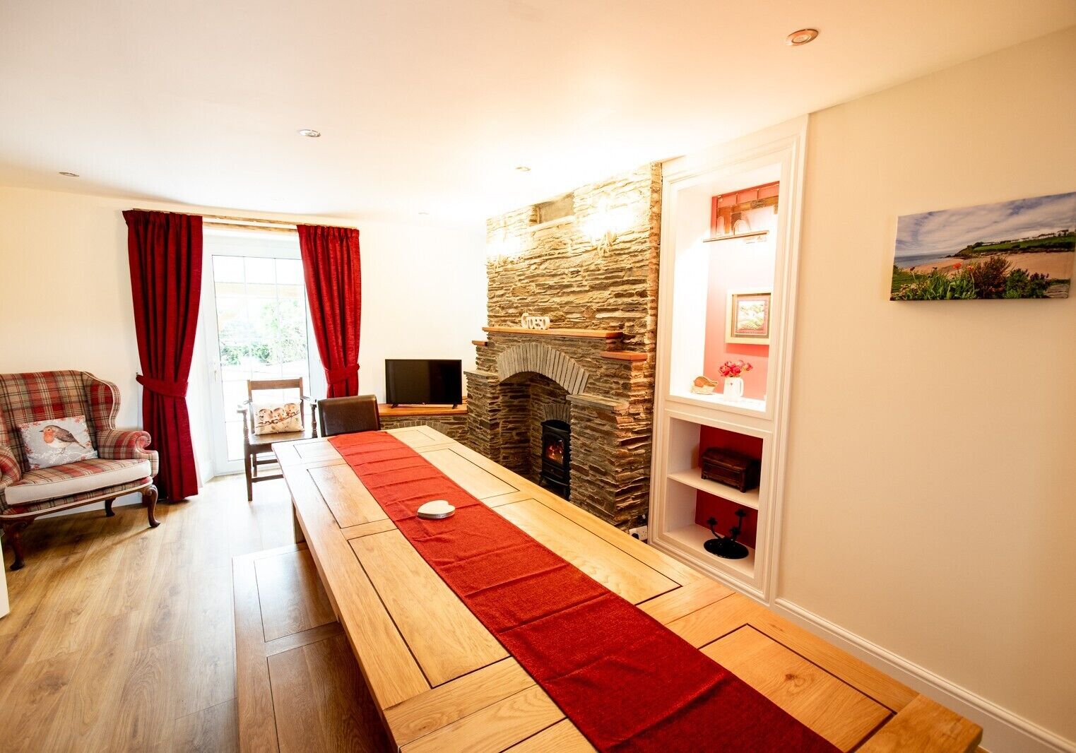 A cozy living room with a stone fireplace, a wooden bench, and a red runner.