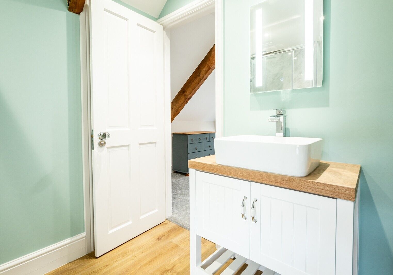 A bathroom with a white sink, a mirror, and a wooden countertop.
