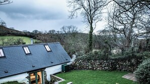 A house with a sloped roof, a stone wall, and a well-maintained lawn.