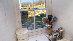 Une cuisine dotée d’une grande fenêtre, d’un bac à compost et de divers ustensiles de cuisine.