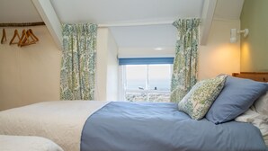 Une chambre à coucher avec un lit, une fenêtre donnant sur un beau paysage et un luminaire suspendu.