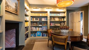A library with bookshelves, a fireplace, and a dining area with a table and chairs. - A stylish house for 6 in the heart of Newport, Pembrokeshire (Newport)